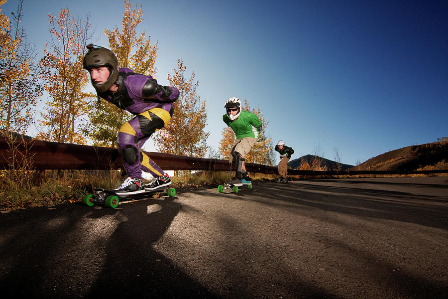 Athlete Photograph - Athletes Longboarding On Road Against Clear Sky by Cavan Images
