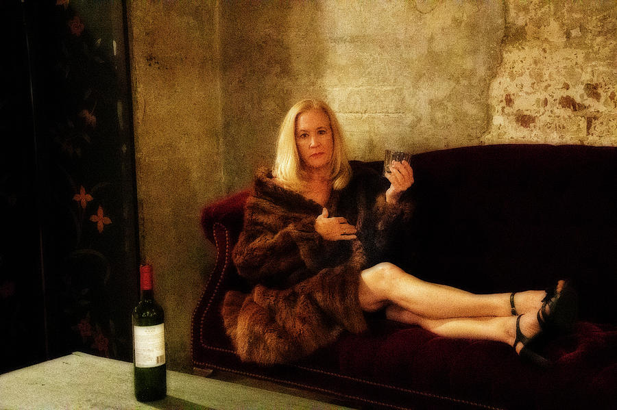 Attractive older woman with drink in her hand on couch in a fur Photograph by Dan Friend