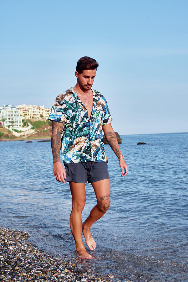 Attractive Young Man Walking Along The Shore Of The Beach Photograph by ...