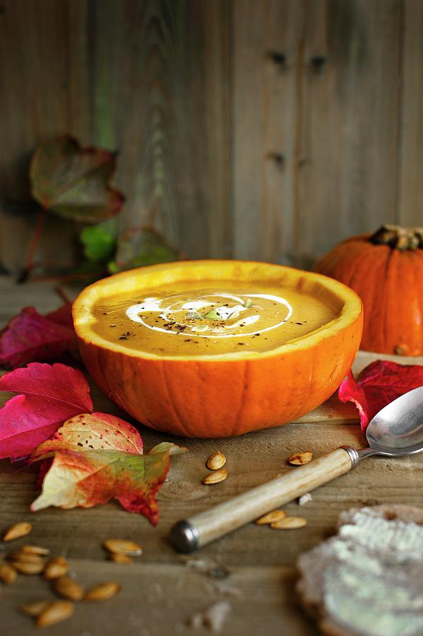 Autumnal Pumpkin Soup Served In A Hollowed Out Pumpkin With Sour Cream And Pumpkin Seeds Photograph by Magdalena Hendey
