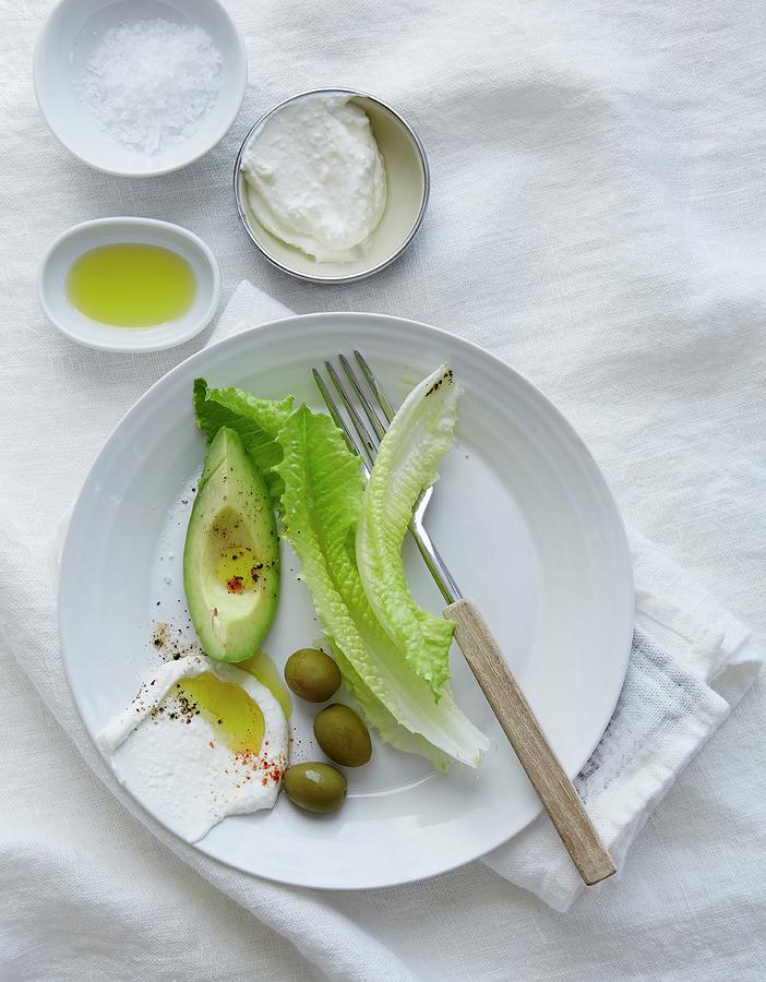 Avocado, Olives, Lettuce Leaves, Olive Oil, Salt And Yoghurt Photograph by Mans Jensen