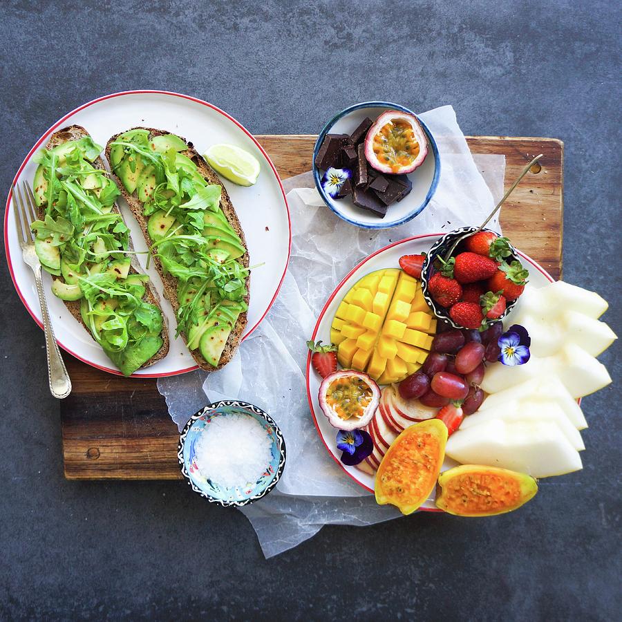 Avocado-rocket Lettuce On Sliced Bread And A Dish Of Fresh Fruit Photograph by Velsberg