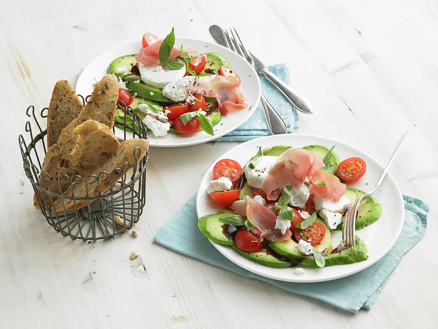 Avocado With Goats Cheese, Raw Ham, Cherry Tomatoes And Wholegrain Baguette Slices Photograph by Nikolai Buroh