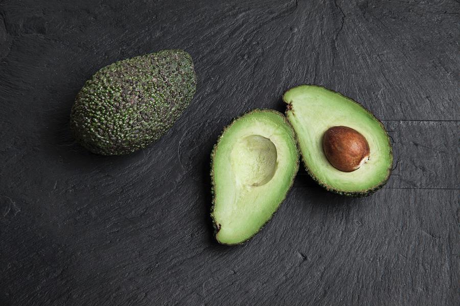 Avocados, Whole And Halved, On A Slate Platter Photograph by Richard Church