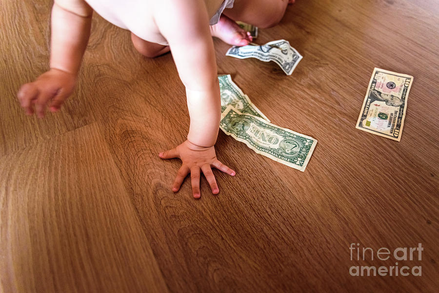 Baby playing with some dollar bills he has found on the floor of Photograph by Joaquin Corbalan