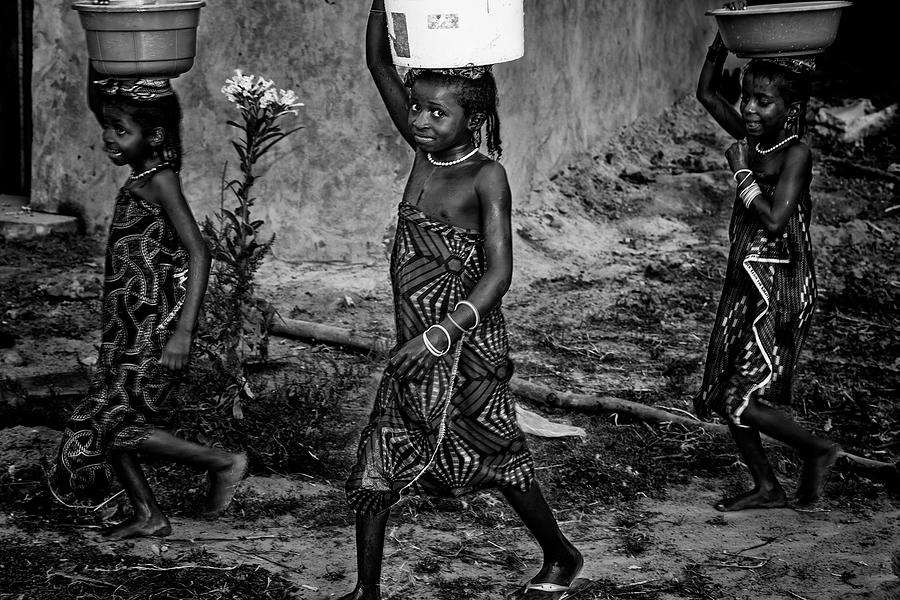 Black And White Photograph - Back Home With The Water - Benin by Joxe Inazio Kuesta Garmendia