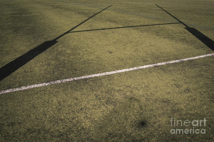 Background of a rugby goal casting shadows on the field. Photograph by Joaquin Corbalan