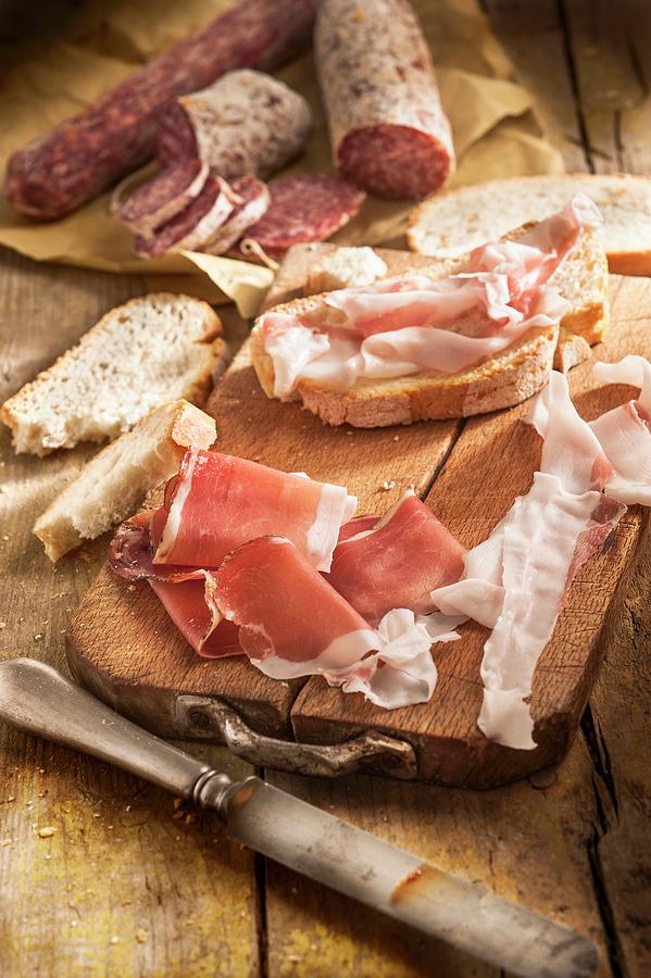 Bacon, Salami And Bread On A Chopping Board Photograph by Piga & Catalano S.n.c.