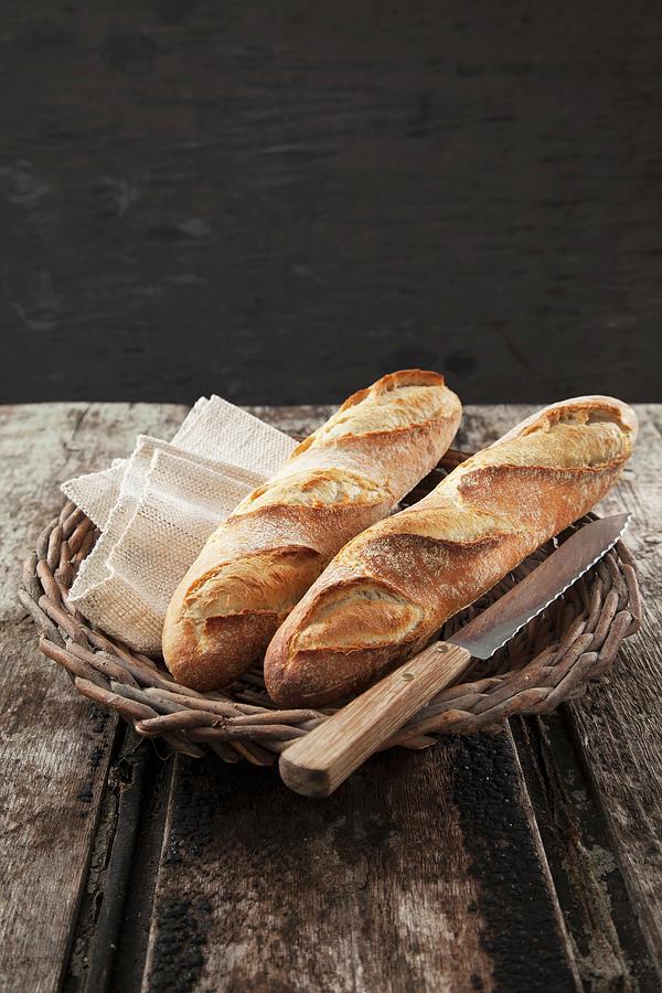 Baguettes In A Basket With A Knife Photograph by Rafael Pranschke