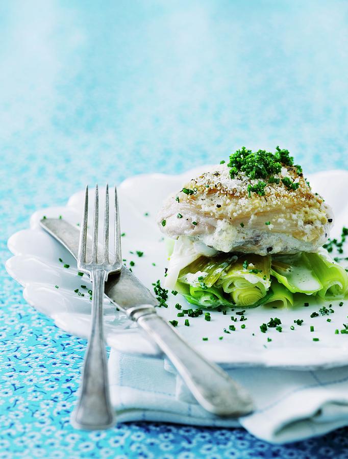 Baked Cod On A Bed Of Leek With Grated Parmesan Cheese, Chives And A White Wine And Cream Sauce Photograph by Mikkel Adsbl