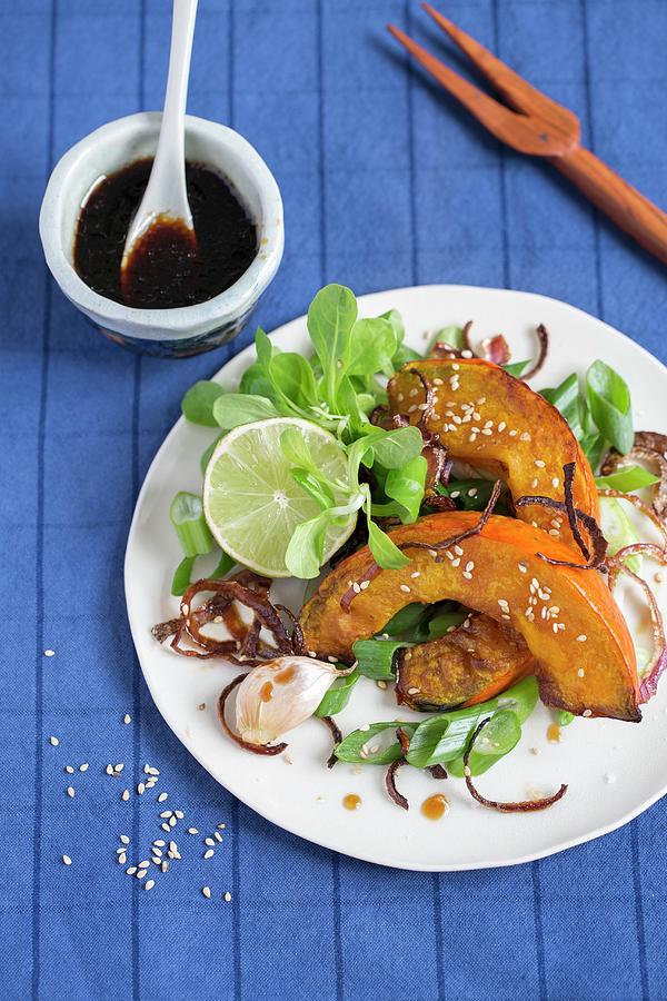 Baked Hokkaido Pumpkin Wedges With Lambs Lettuce And Soy Sauce Photograph by Tina Engel