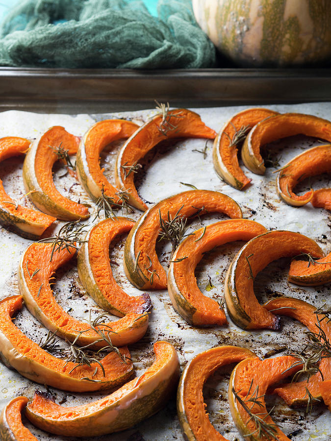 Baked Pumpkin Slices On Baking Parchment With Rosemary Photograph by Sofya Bolotina