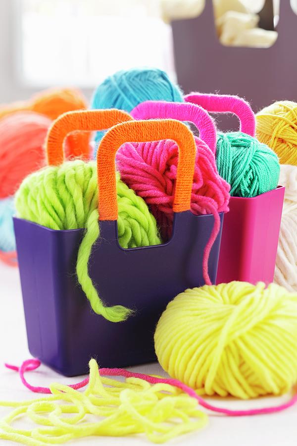 Balls Of Brightly Coloured Wool In Purple Plastic Bags With Wool-wrapped Handles Photograph by Franziska Taube