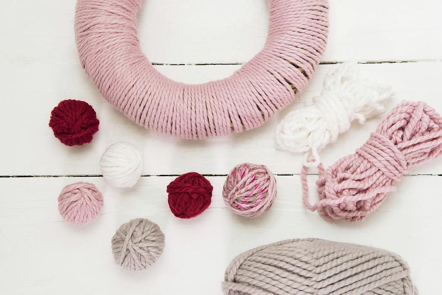 Balls Of Wool And Wreath Wrapped In Pink Yarn On White Surface Photograph by Vierucci/eustachi
