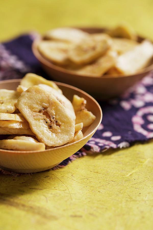 Banana Chips In Wooden Bowls On Banana Paper Photograph by Mandy Reschke
