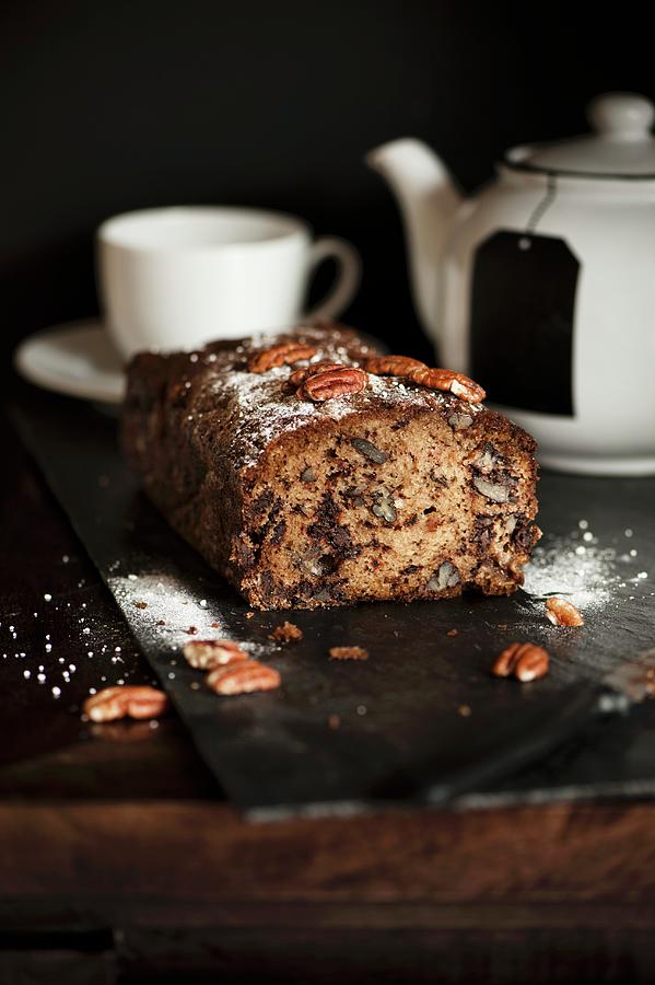 Banana, Chocolate And Pecan Nut Bread In Front Of A Teapot And A Tea Cup Photograph by Magdalena Hendey