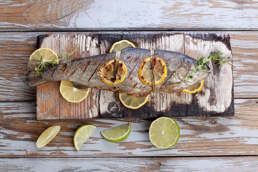 Barbecued Trout With Lemons And Limes On A Wooden Board Photograph by Wawrzyniak.asia