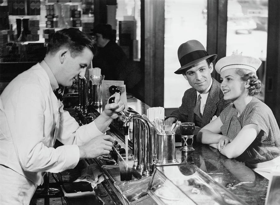 Bartender Pouring Beer For Young Couple Photograph by George Marks