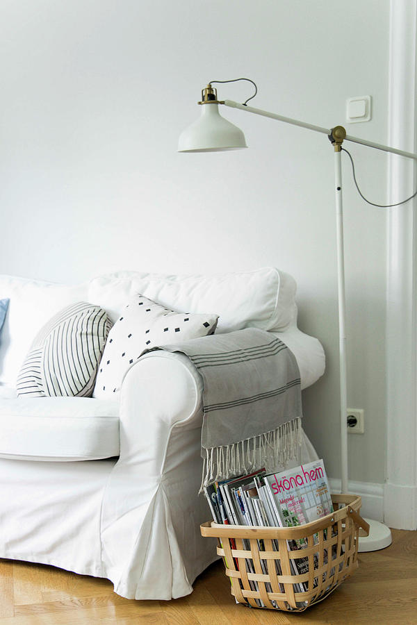 Basket Of Magazines And Standard Lamp Next To Sofa Photograph by Ilaria Chiaratti