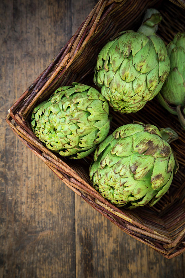 Basket Of Organic Artichokes On Wooden Photograph by Westend61