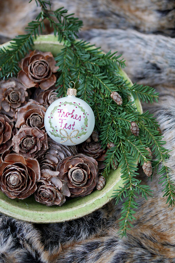 Bauble With Christmas Greeting And Larch Cones In Bowl Photograph by Angelica Linnhoff