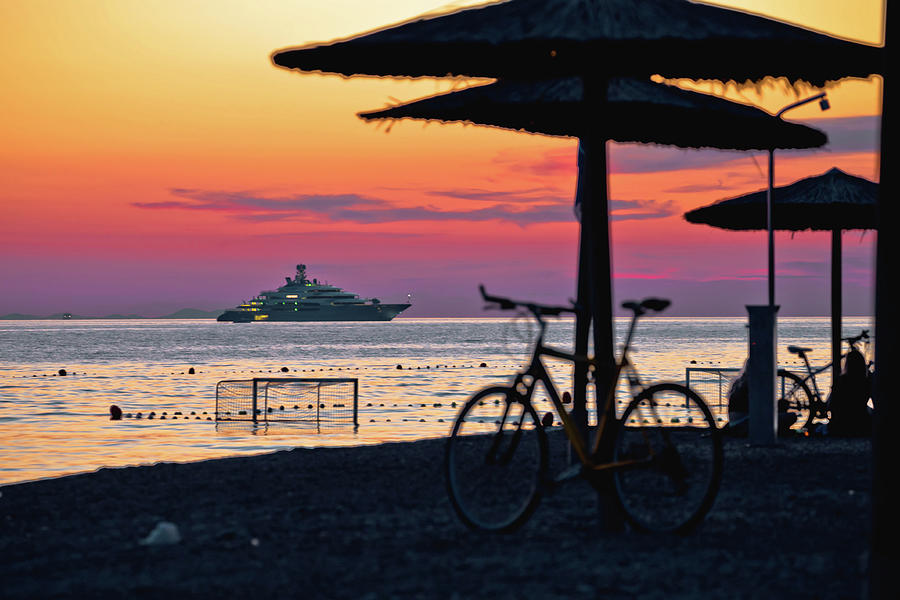 Beach and parasols on colorful sunset with large yacht view Photograph by Brch Photography