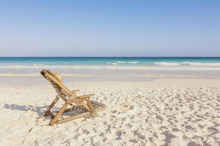 Beach Chair With Hat On Beach Next To Photograph by Sasha Weleber