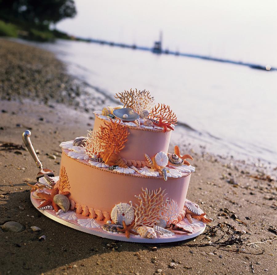 Beach Themed Wedding Cake On The Sand At Waters Edge Photograph by Cooke, Colin