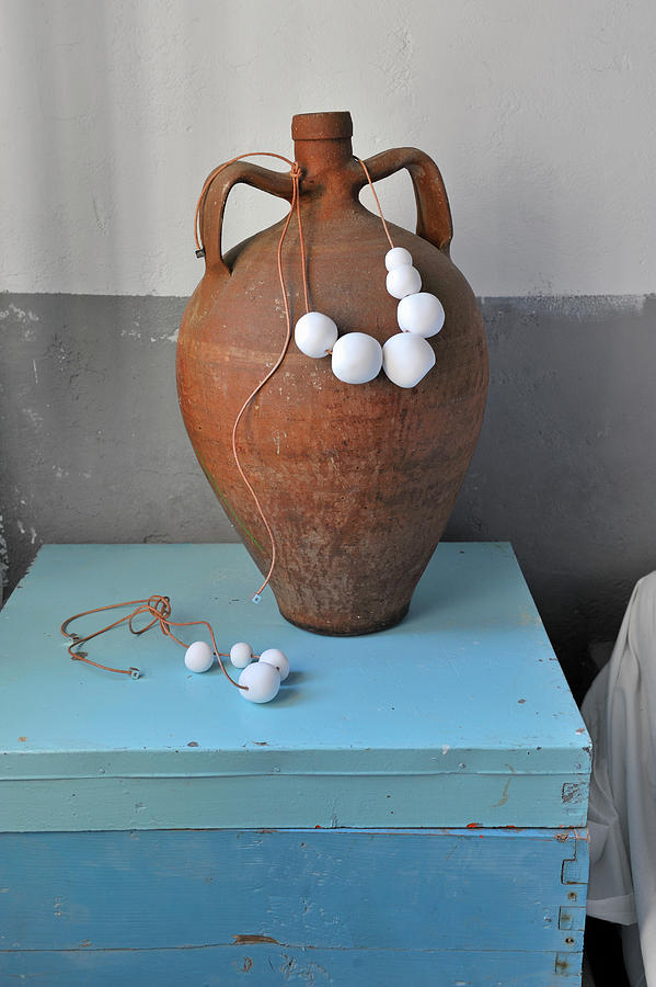 Bead Necklace Around Clay Amphora On Light Blue Wooden Box Photograph by Henri Del Olmo