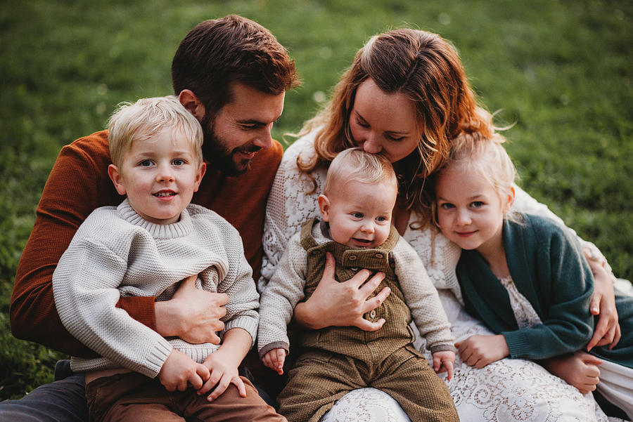 Beautiful Family Sitting In A Park Mom Kissing The Baby Photograph by ...