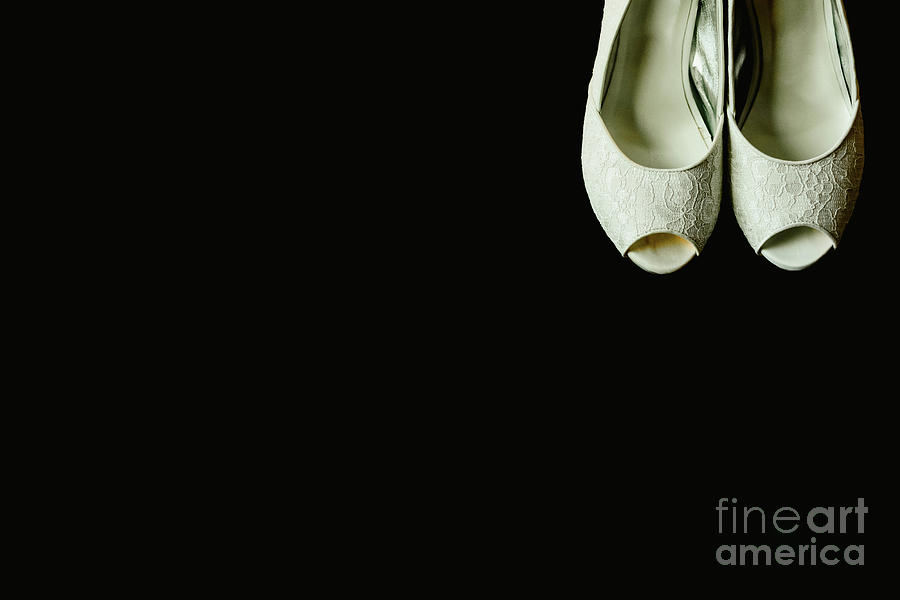 Beautiful white wedding shoes in a corner on isolated black background, copy space. Photograph by Joaquin Corbalan