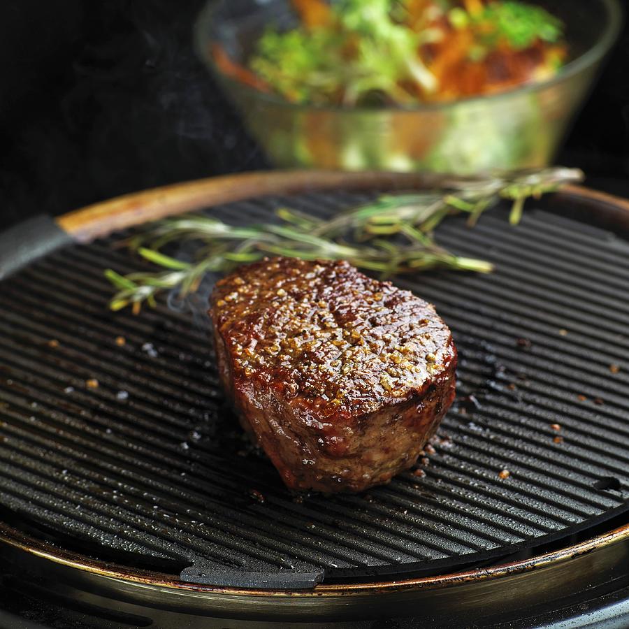 Beef Fillet Steak On A Grill In Front Of A Salad Bowl Photograph by Herbert Lehmann
