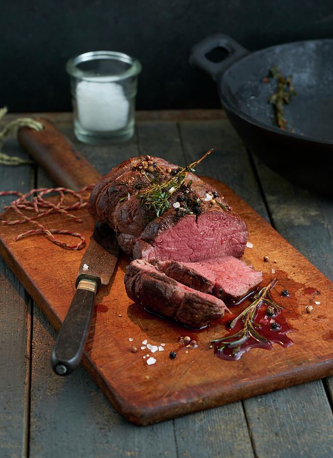 Beef Fillet With Rosemary On A Rustic Wooden Board Photograph by Stefan Schulte-ladbeck