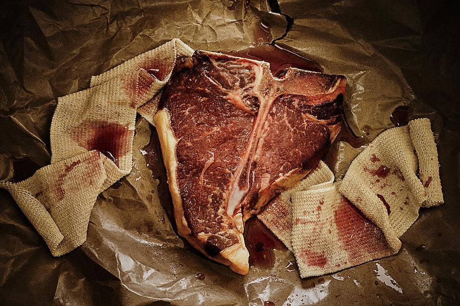 Beef Steak On A Piece Of Paper With A Bloody Bandage Photograph by Colin Cooke