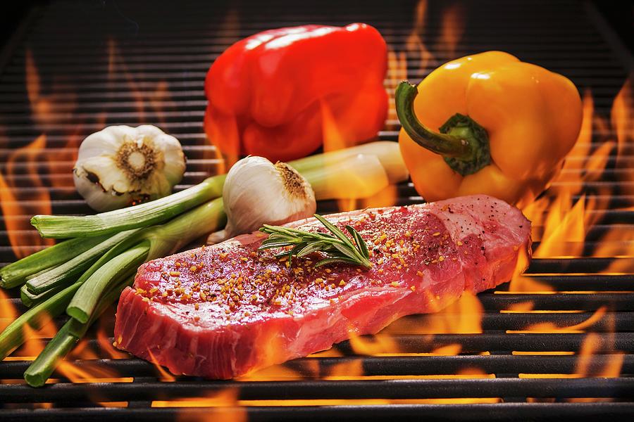 Beef Steak With Rosemary, Red And Yellow Peppers, Fresh Garlic And Spring Onions On A Flaming Barbecue Photograph by Brian Enright