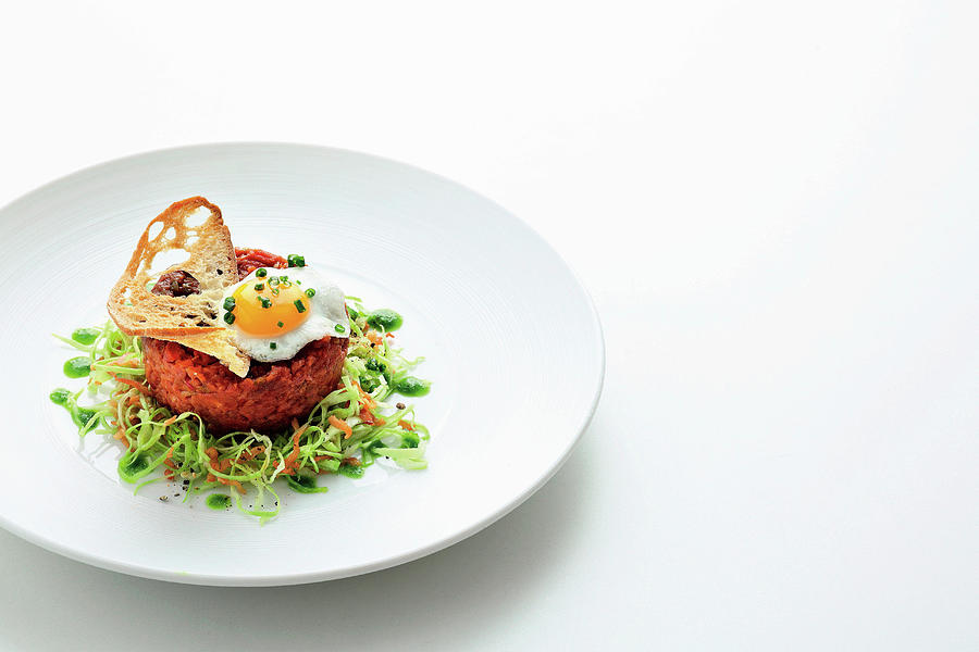 Beef Tartare With A Fried Quail Egg, A Bread Chip, Pointed Cabbage And Chive Oil Photograph by Jalag / Mathias Neubauer