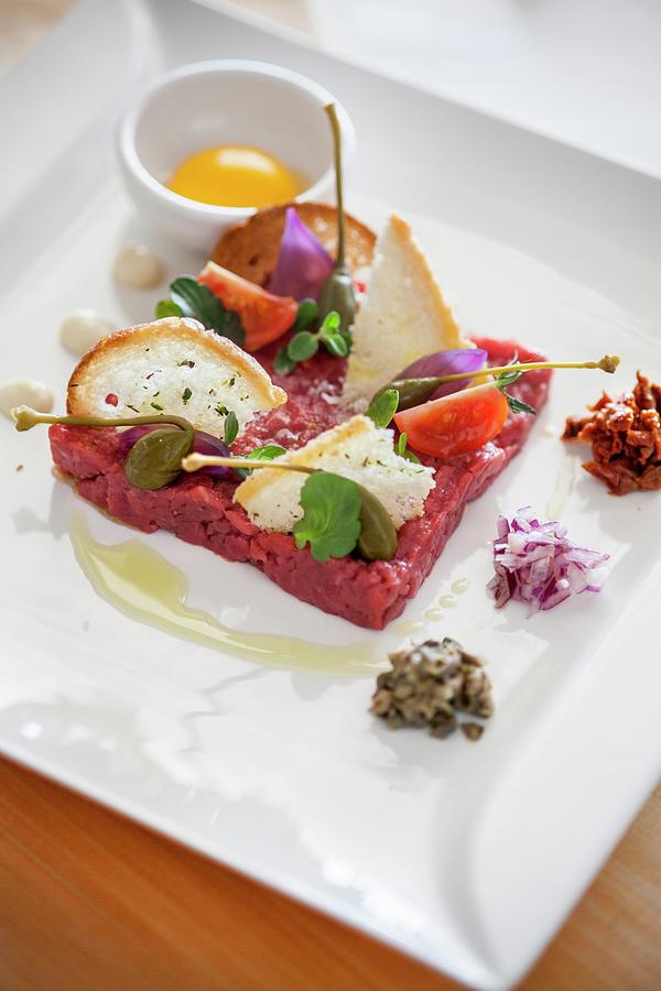 Beef Tartare With Capers, Chopped Onion, Dried Tomatoes In Oil And Croutons, Next To An Egg Yolk In Bowl Photograph by Imagerie