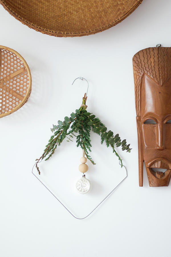 Bent Metal Coat Hanger Decorated With Twigs On Wall Next To Ethnic Mask Photograph by Marij Hessel