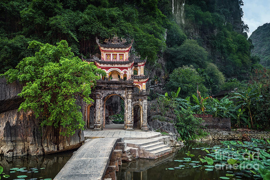 Premium Photo  Lone tourist with traditional vietnamese hat at bich dong  pagoda entrance gate, ninh binh vietnam, buddhist temple set amid jungle  and karst mountain range. traveling alone, keep social distancing.