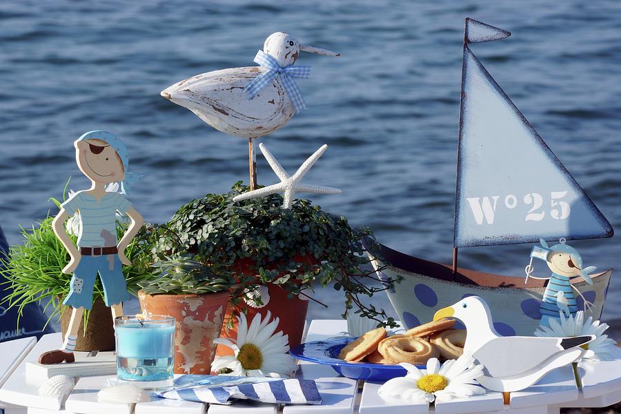 Biscuits On Plate Surrounded By Maritime Ornaments On White Table Against Ocean Backdrop Photograph by Angelica Linnhoff