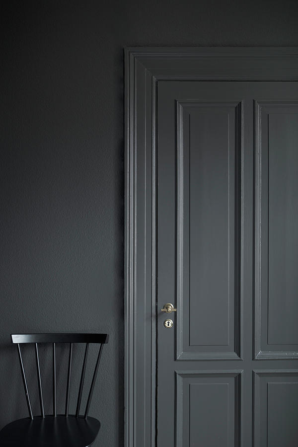 Black Chair Against Grey Wall With Grey Panelled Door Photograph by Bjarni B. Jacobsen