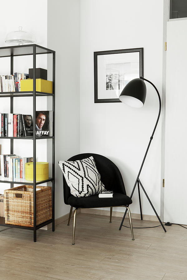 Black Chair With Scatter Cushion Between Standard Lamp And Shelves In Corner Photograph by Hej.hem Interior