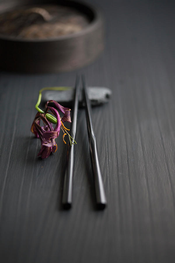 Still Life Photograph - Black Chopsticks Next To Dried Gloriosa Lily by Martina Schindler