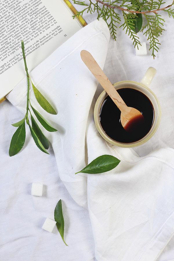 Black Coffee And A Cop With A Wooden Spoon With Sugar Cubes And Leaves Next To It Photograph by Zita Csig