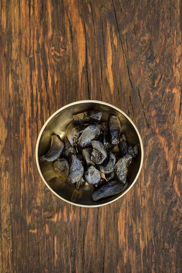 Black Fermented Garlic In A Golden Bowl Photograph by Elisabeth Clfen