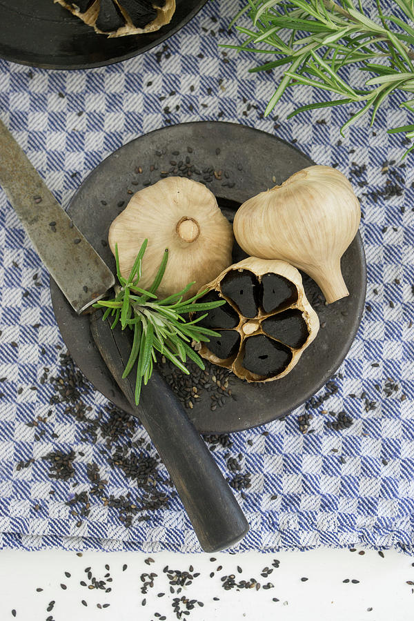 Black Garlic With Rosemary Photograph by Martina Schindler