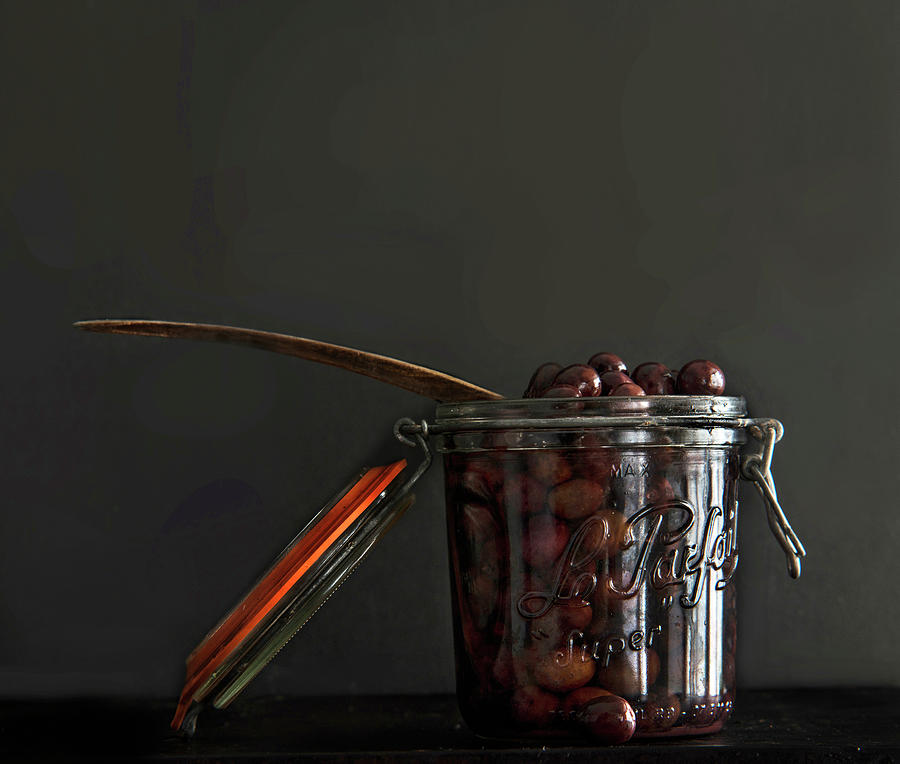 Black Olives In A Jar Against A Black Background Photograph by Roger Stowell