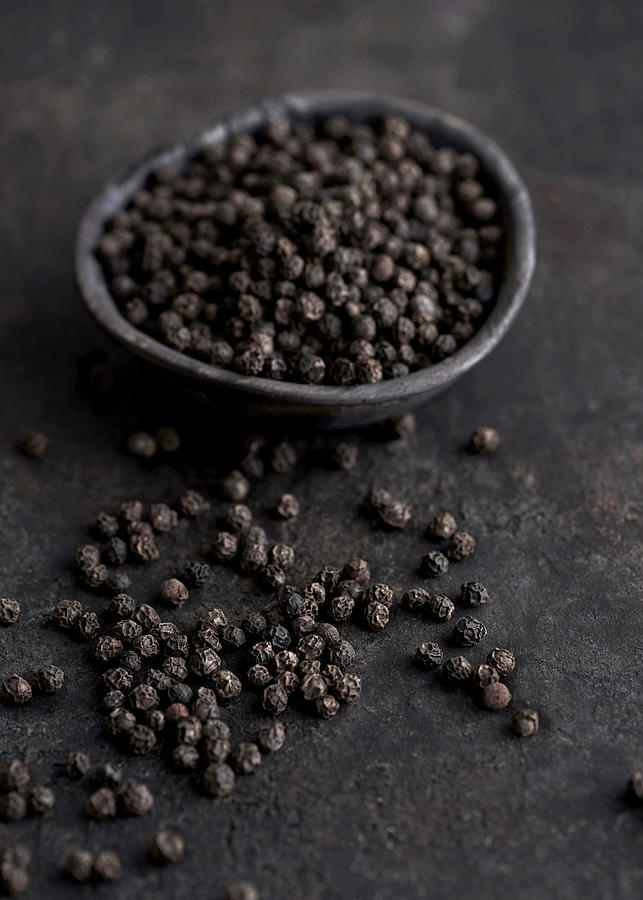 Black Peppercorns In A Black Wooden Bowl And On A Black Metal Surface Photograph by Sylvia Meyborg