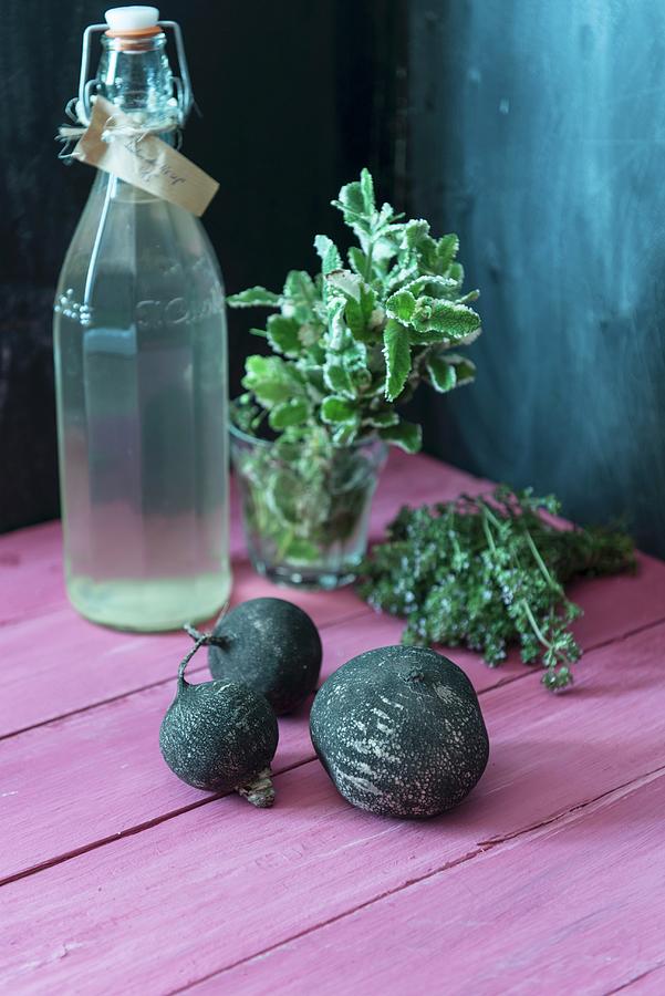 Black Radishes, A Bottle Of Elderflower Syrup, Apple Mint And Thyme Photograph by Angelika Grossmann