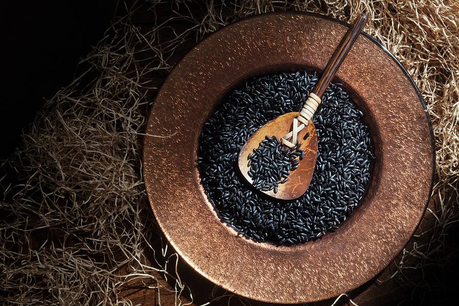 Black Rice In A Copper Dish With A Wooden Spoon Seen From Above Photograph by Katharine Pollak